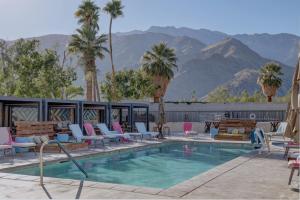 una piscina con sillas, una mesa y montañas en The Infusion Beach Club, en Palm Springs