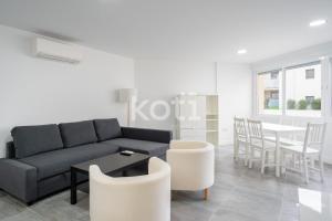 uma sala de estar com um sofá, uma mesa e cadeiras em Koti Rentals - Colina Blanca em Fuengirola