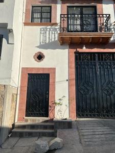a building with two black doors and a balcony at Departamentos huerta in Taxco de Alarcón