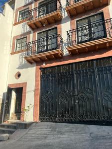 a building with a black gate and balconies on it at Departamentos huerta in Taxco de Alarcón