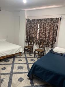 um quarto com 2 camas e 2 cadeiras e uma janela em Departamentos huerta em Taxco de Alarcón