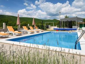a pool with chairs and umbrellas in a resort at Kuća za odmor Silvano in Dicmo