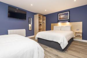a bedroom with two beds and a tv on the wall at Port 56 in Portstewart
