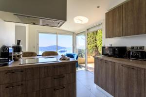 a kitchen with wooden cabinets and a large window at VILLA BELLE VUE VI4394 By Riviera Holiday Homes in Villefranche-sur-Mer