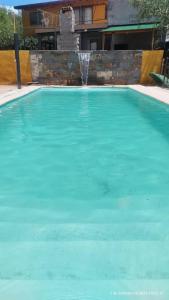 une grande piscine d'eau bleue avec une fontaine dans l'établissement Hermosa casa en barrio la toma, à Capilla del Monte