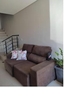 a brown leather couch in a living room at Geminado Ibicaré com quarto privativo em casa compartilhada in Joinville