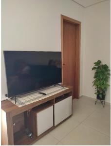 TV de pantalla plana grande en un soporte de madera en Geminado Ibicaré com quarto privativo em casa compartilhada en Joinville