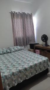 1 dormitorio con cama, escritorio y ventana en Geminado Ibicaré com quarto privativo em casa compartilhada, en Joinville