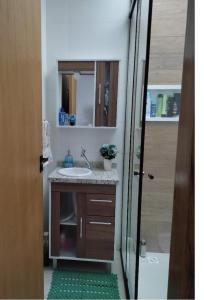 a bathroom with a sink and a mirror at Geminado Ibicaré com quarto privativo em casa compartilhada in Joinville