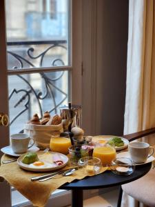 uma mesa de pequeno-almoço com alimentos de pequeno-almoço e sumo de laranja em La Maison De Blanche em Bordeaux