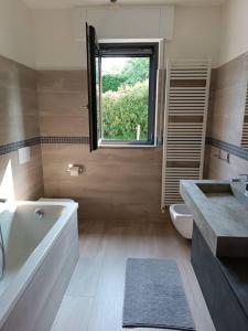 uma casa de banho com uma banheira, um WC e uma janela. em appartamento immerso nel verde tra laghi e colline em Anzano del Parco