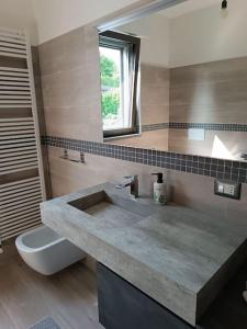 uma casa de banho com um lavatório, um WC e uma janela. em appartamento immerso nel verde tra laghi e colline em Anzano del Parco