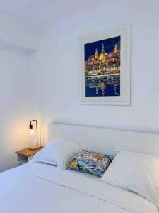 Un dormitorio con una cama blanca con una foto en la pared en Menton - Vue panoramique exceptionnelle ! 4Pers en Menton