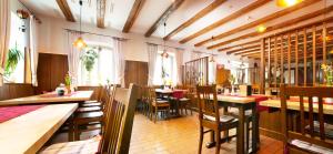 a restaurant with wooden tables and chairs and windows at Hotel zum Alten Wirt in Langenbach