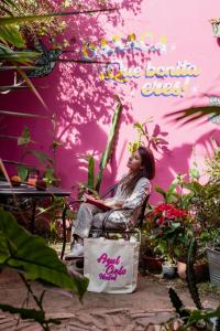 una mujer sentada en una silla frente a una pared rosa en Azul Cielo Hostel, en Oaxaca City