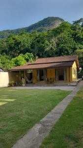 a small yellow house with a grassy yard at Casa Temporada in Rio de Janeiro