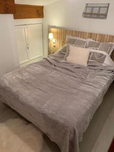 孔布卢Chalet le Daim appartement 6 pers Vue Mont-Blanc的卧室配有一张大床,提供灰色床单和枕头