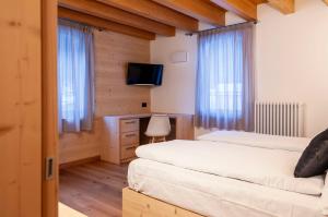 een slaapkamer met 2 bedden, een tv en ramen bij Antico Borgo Palue in Sottoguda