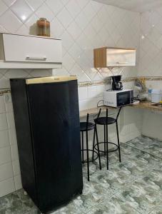 une cuisine avec des chaises et un comptoir avec un four micro-ondes dans l'établissement Quarto/sala Região central, à Macaé