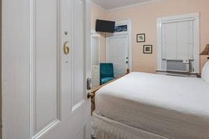 Un dormitorio blanco con una cama y un televisor. en Curry House Room 6, en Key West