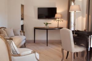 a living room with a table and chairs and a tv at Benvengudo in Les Baux-de-Provence