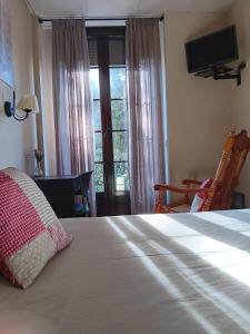 a bedroom with a bed and a window with a television at Hostal La Cigueña in El Espinar