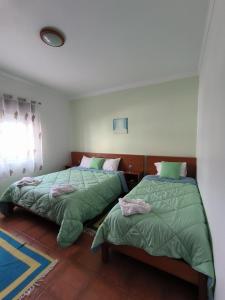 two beds sitting next to each other in a bedroom at Apartamentos Campos 2 in Porto Covo