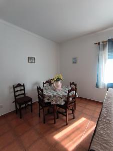 a dining room table with chairs and a vase of flowers on it at Apartamentos Campos 2 in Porto Covo