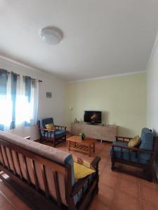 a living room with couches and a flat screen tv at Apartamentos Campos 2 in Porto Covo