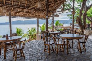 un restaurante con mesas y sillas y vistas al agua en Paradiso Hostel, en La Laguna