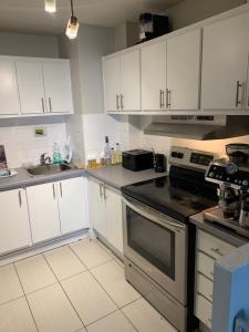 uma cozinha com armários brancos e um forno com placa de fogão em Appartement 2 Chambre neuf em Longueuil
