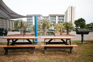 Deux tables de pique-nique dans un parc avec des bâtiments en arrière-plan dans l'établissement GRAND STRAND FUN WITH SO MUCH TO DO - EVEN PICKLEBALL!, à Myrtle Beach