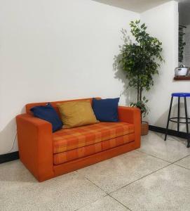 an orange couch with blue and yellow pillows on it at Lindo apto amoblado ¡super central! RNT734 in Armenia