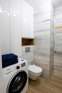 a bathroom with a washing machine and a toilet at Apartament Sunny Five in Suwałki