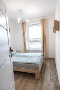 a small bedroom with a bed and a window at Apartament Sunny Five in Suwałki