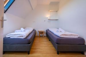 two beds in a small room with a table at De Waddenparel in Kinnum
