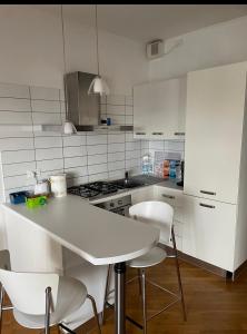 una cucina con armadi bianchi, tavolo e sedie di La casa di LUCA a Imola
