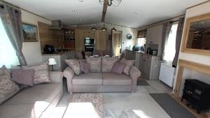 a living room with a couch and a kitchen at Binka - Luxury 40 x 14ft Lodge in Tain