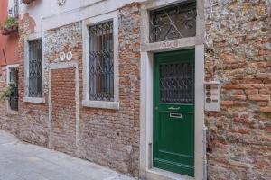a green door on the side of a brick building at Ca' Spritz - Home in Venice