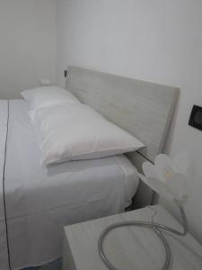 een wit bed met een wit kussen en een tafel bij La tua casa tra Milano e Como in Caronno Pertusella