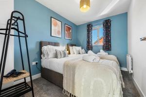 - une chambre avec des murs bleus et un grand lit dans l'établissement Stylish 4-Bedroom Townhouse with two large parking spaces and superfast Wi-Fi, à Gloucester