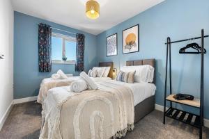 two beds in a room with blue walls at Stylish 4-Bedroom Townhouse with two large parking spaces and superfast Wi-Fi in Gloucester