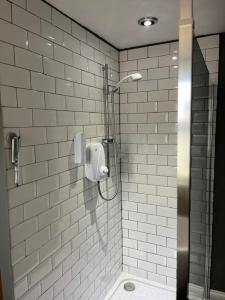 a shower stall in a bathroom with white tiles at Most Easterly - The Loft in Pakefield