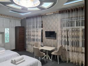 a hotel room with two beds and a table and a tv at Nazarxan Hotel in Samarkand