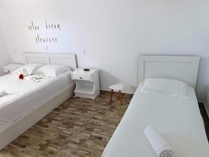 a white bedroom with two beds and a table at Sweet Home Nikorenia 2 in Krotiri