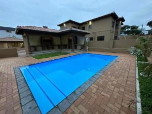 a large blue swimming pool in front of a house at Six64 on KINGSWAY B5 in Amanzimtoti