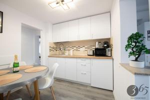 a kitchen with white cabinets and a table with chairs at 365 Guest Apartment in Hunedoara