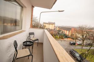un balcón con 2 sillas y un coche en una calle en 365 Guest Apartment, en Hunedoara