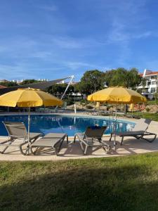 dwa krzesła i dwa parasole przy basenie w obiekcie House of Rising Sun w mieście Quarteira