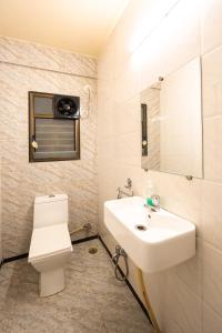 La salle de bains est pourvue d'un lavabo blanc et de toilettes. dans l'établissement Kedari Residency, à Yeraoda